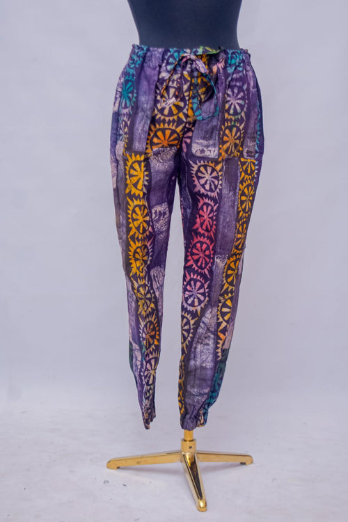 African Batik Tapered Jogger Pants — Purple & Gold Sunwheel Medallion Print with Drawstring Waist, close-up front view